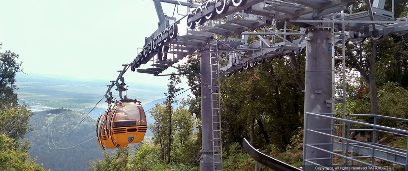 Ropeway systems for remote & hilly connectivity gently carrying passengers over green hills with a scenic valley below.