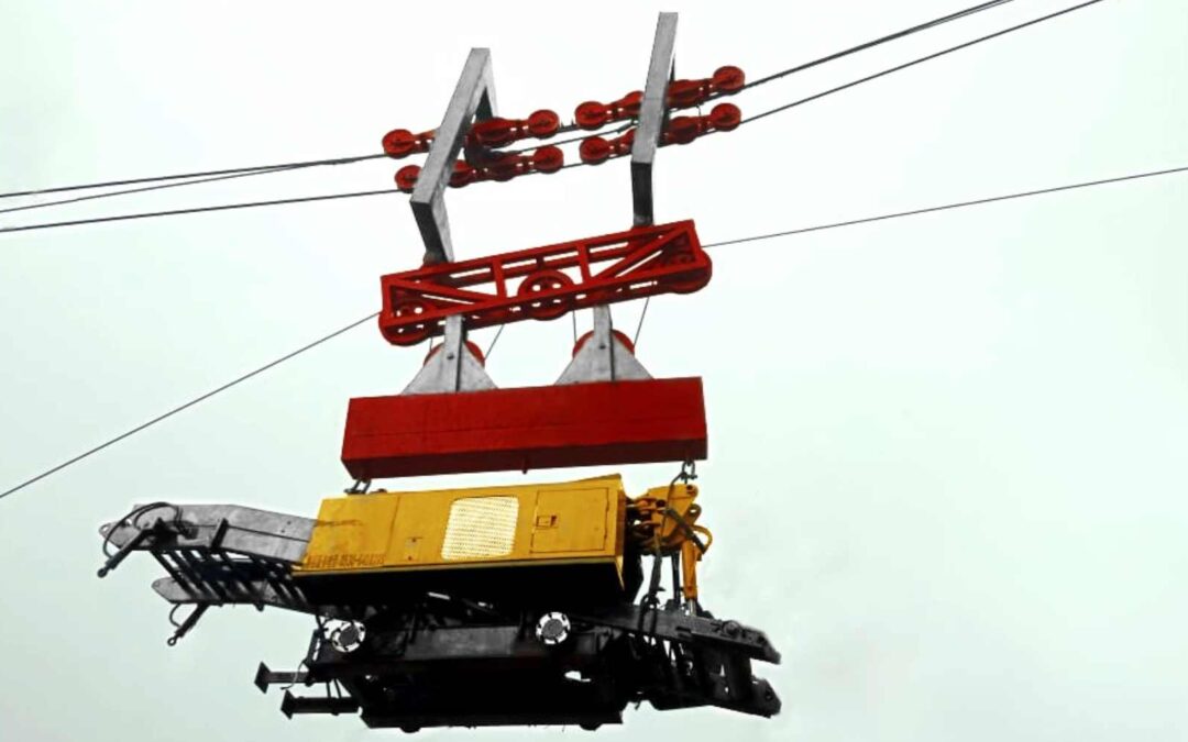 A maintenance carriage hanging from overhead cables, part of Aerial Ropeways & Cable Cranes, used for repair and inspection work.