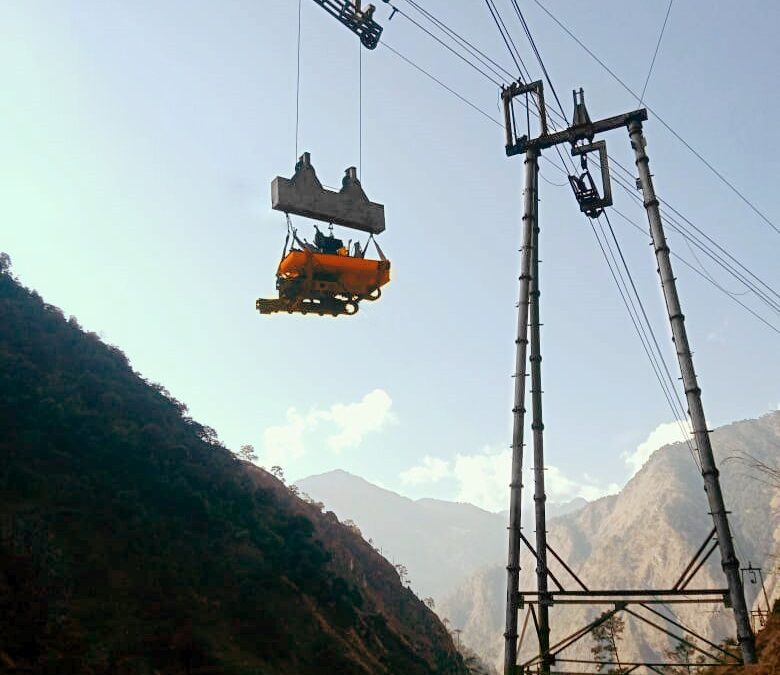 Modern Ropeway Technology lifting heavy equipment via cable system across mountainous terrain with support tower and scenic valley backdrop